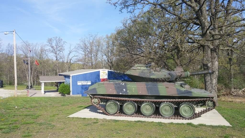 The Marine Corps League Detachment 1137 building seen from the road, with the detachment tank displayed on a concrete pad in front and the American, POW/MIA and Marine Corps flags flying beside it.