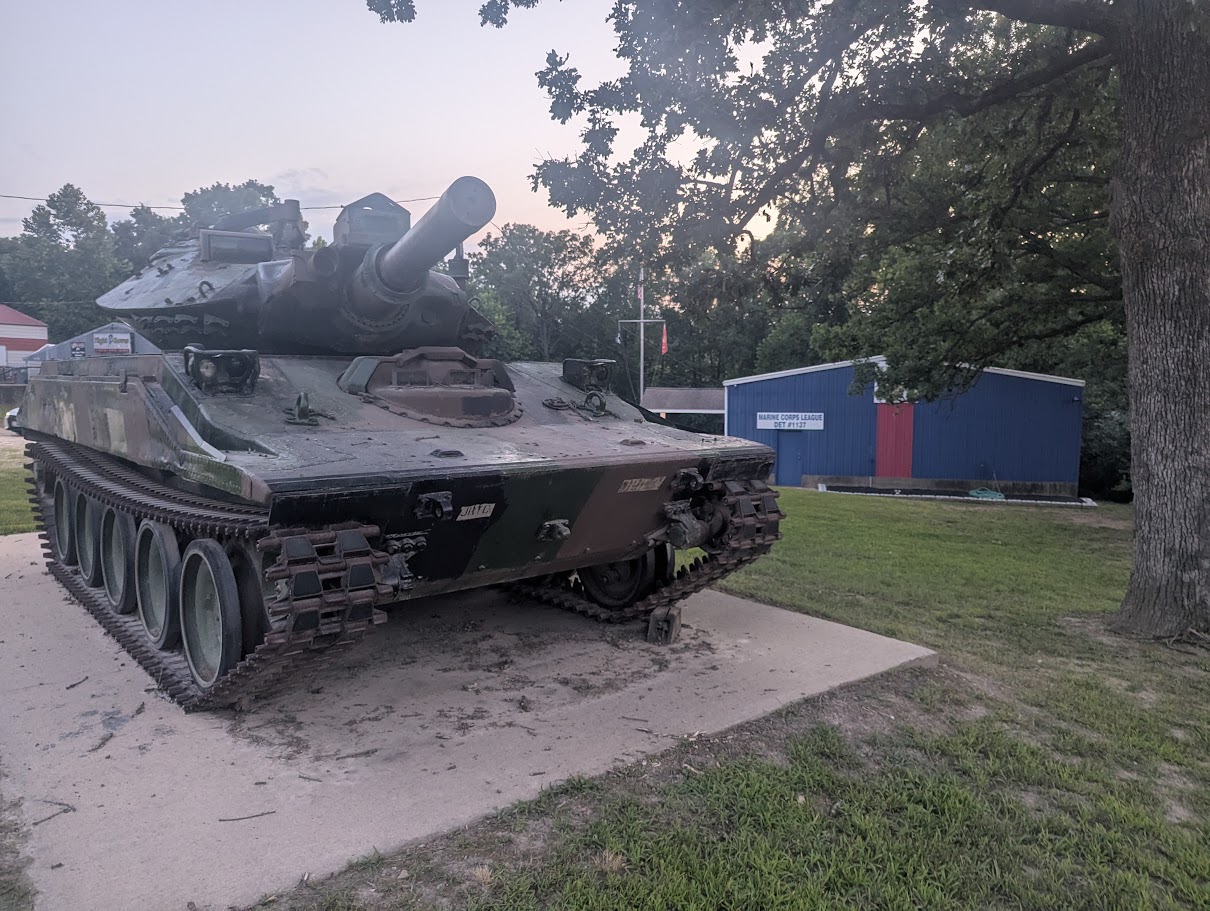 The detachment tank on its concrete display pad at dusk, with the Marine Corps League Detachment 1137 building and its red doors behind it.